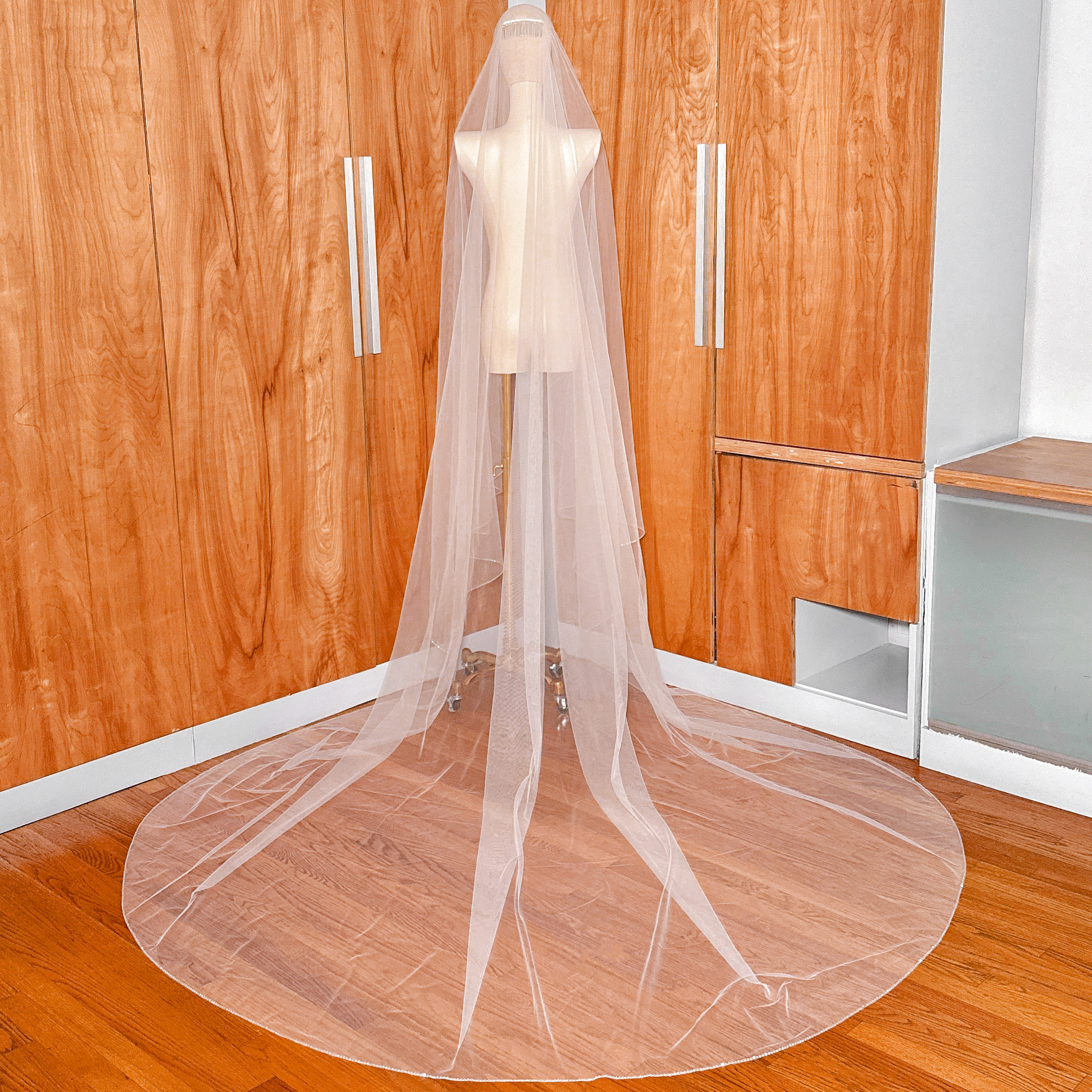 Full-length back view of a cascading two-tier wedding veil with rhinestone edge in cathedral length.