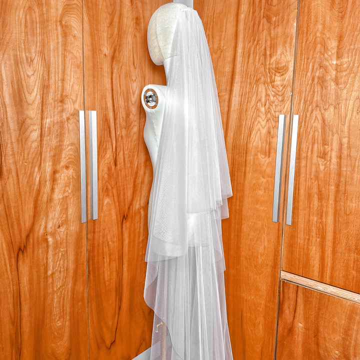 Top-down perspective of a simple soft two-tier cathedral length bridal veil on a mannequin.