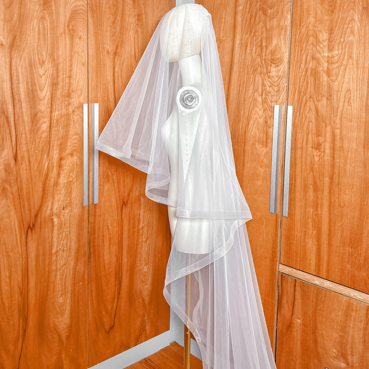 Side view of a 1 1/2" horsehair trim wedding veil with blusher at cathedral length on a mannequin.