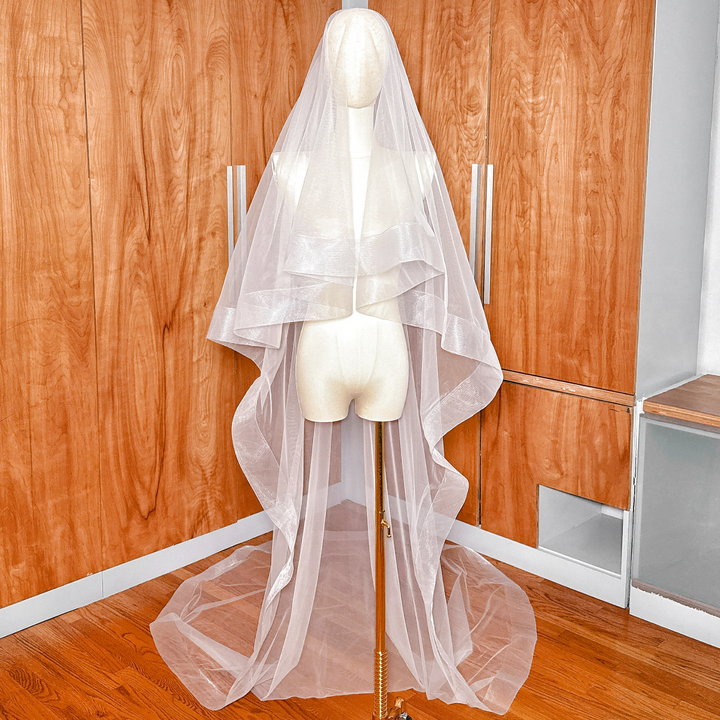 Front view of a two tier cathedral length wedding veil featuring a 3 inch horsehair edge and blusher.