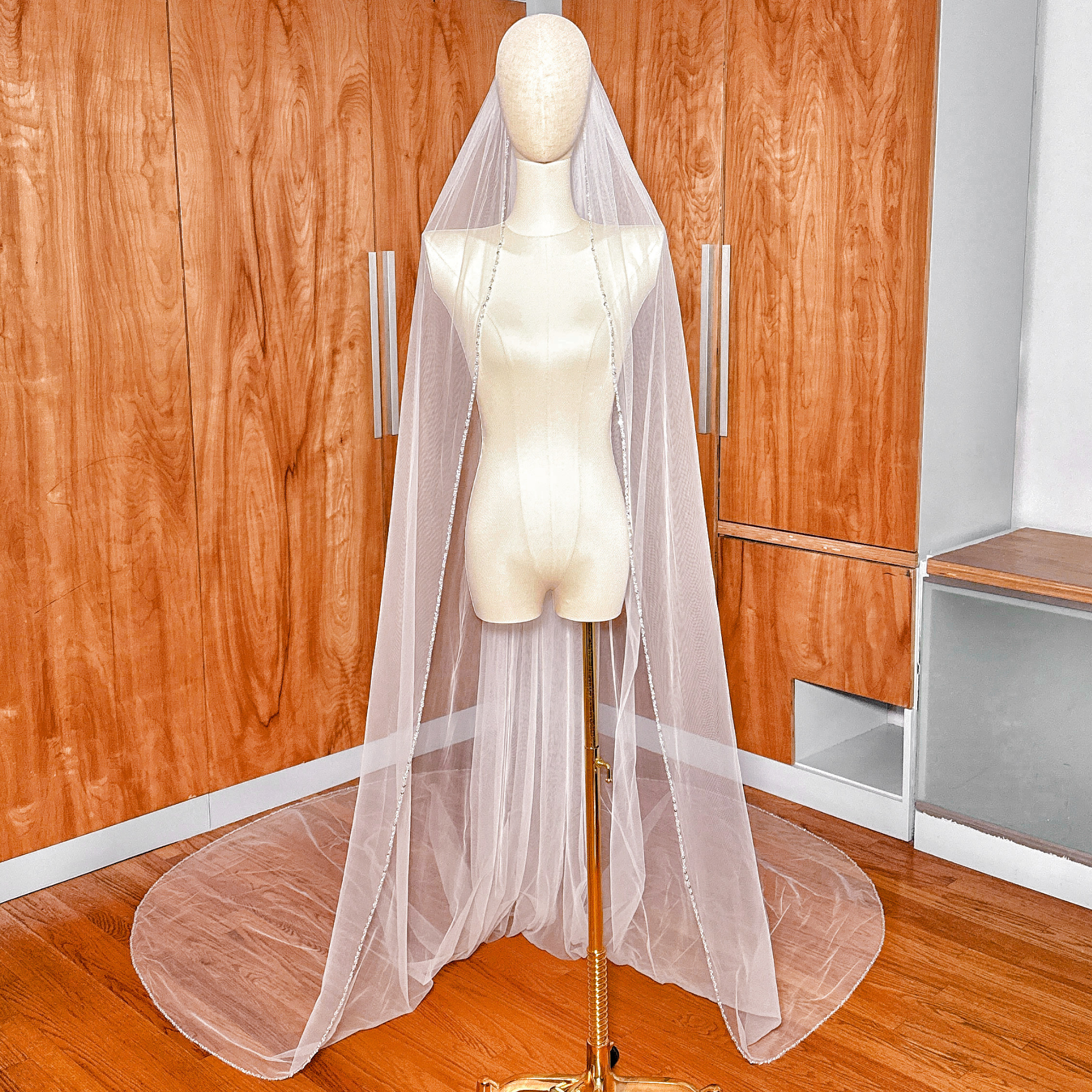 Full-length view of a ivory cathedral wedding veil featuring a delicate beaded edge finish.