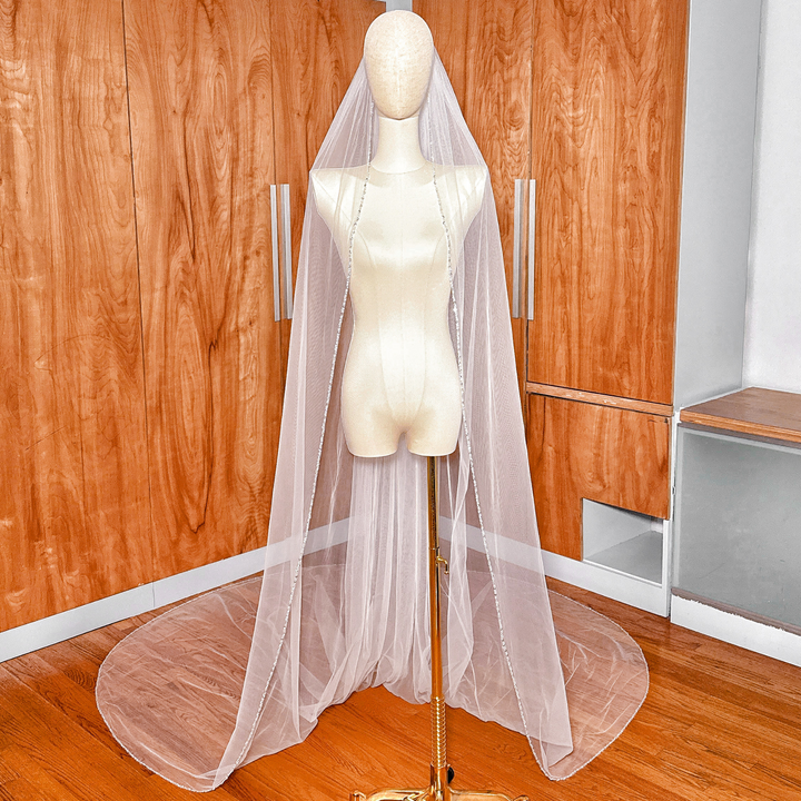 Full-length view of a ivory cathedral wedding veil featuring a delicate beaded edge finish.