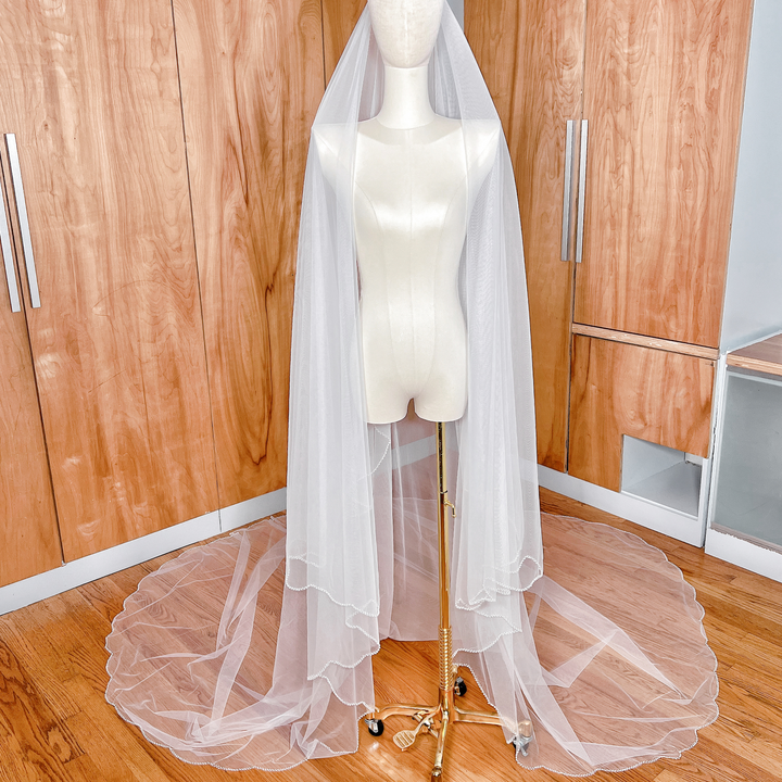 Long cathedral length wedding veil featuring a delicate pearl edge and a sheer blusher tier.