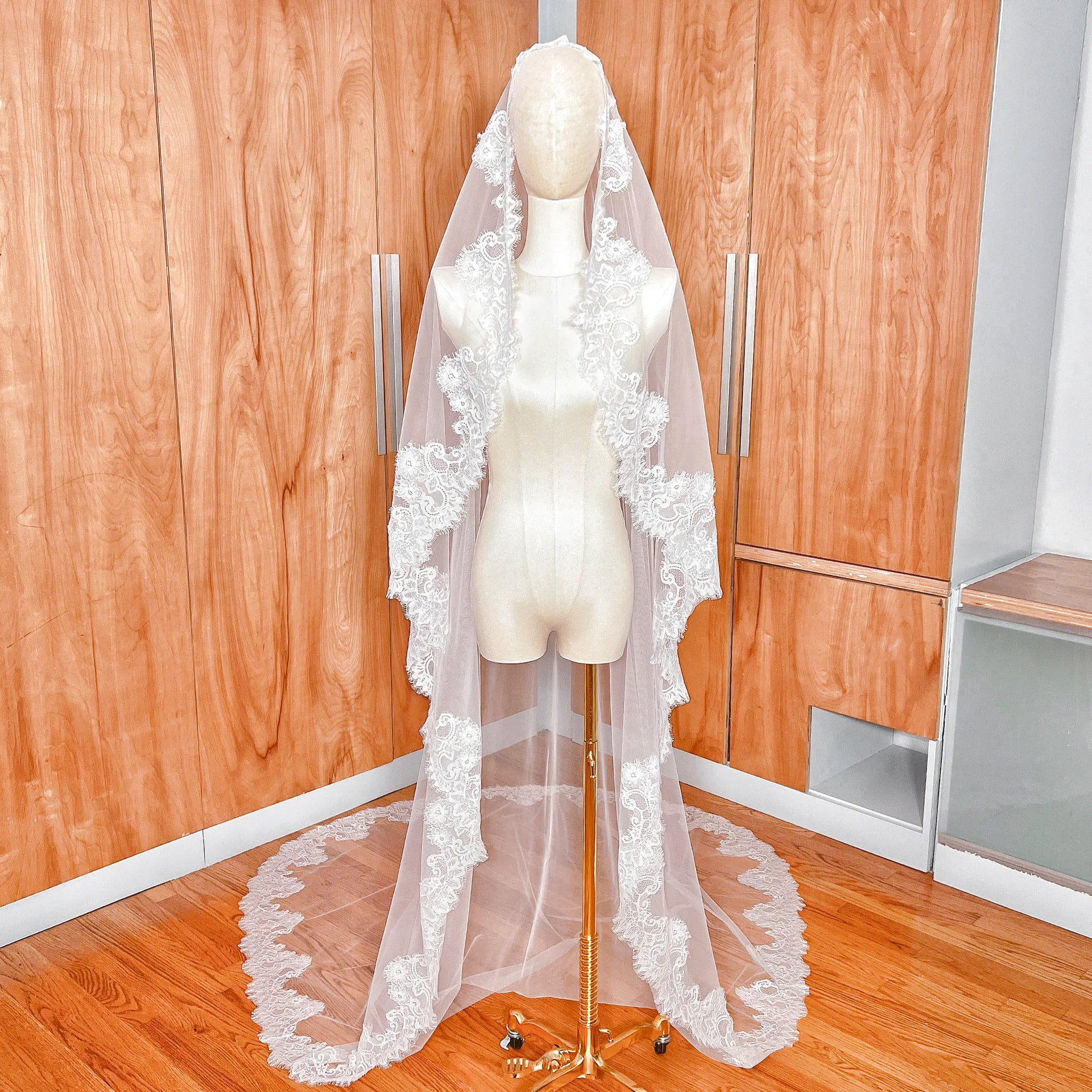 Front view of a cathedral length Chantilly lace bridal mantilla veil draped over a mannequin.