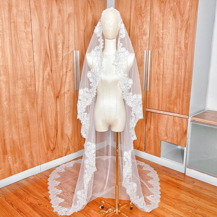 Front view of a cathedral length Chantilly lace bridal mantilla veil draped over a mannequin.