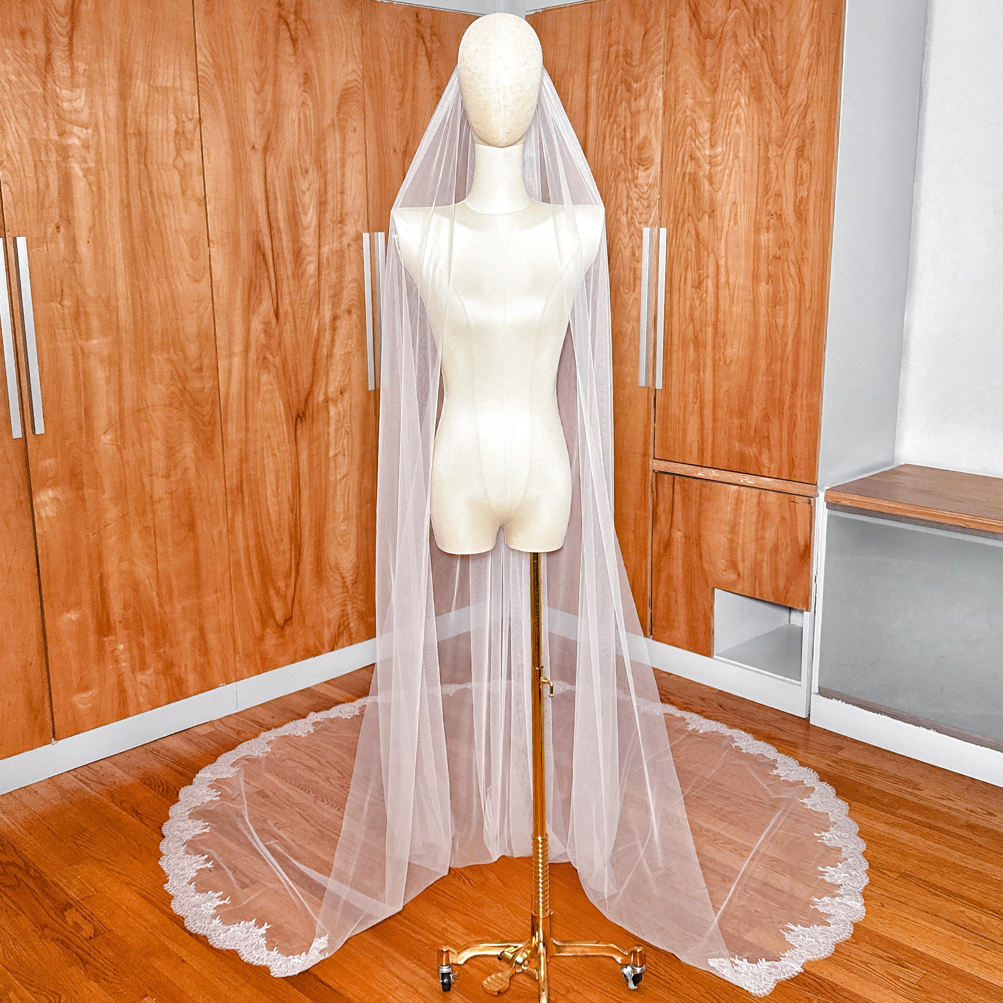 Front view of a Chantilly lace cathedral wedding veil draped over a bridal mannequin.