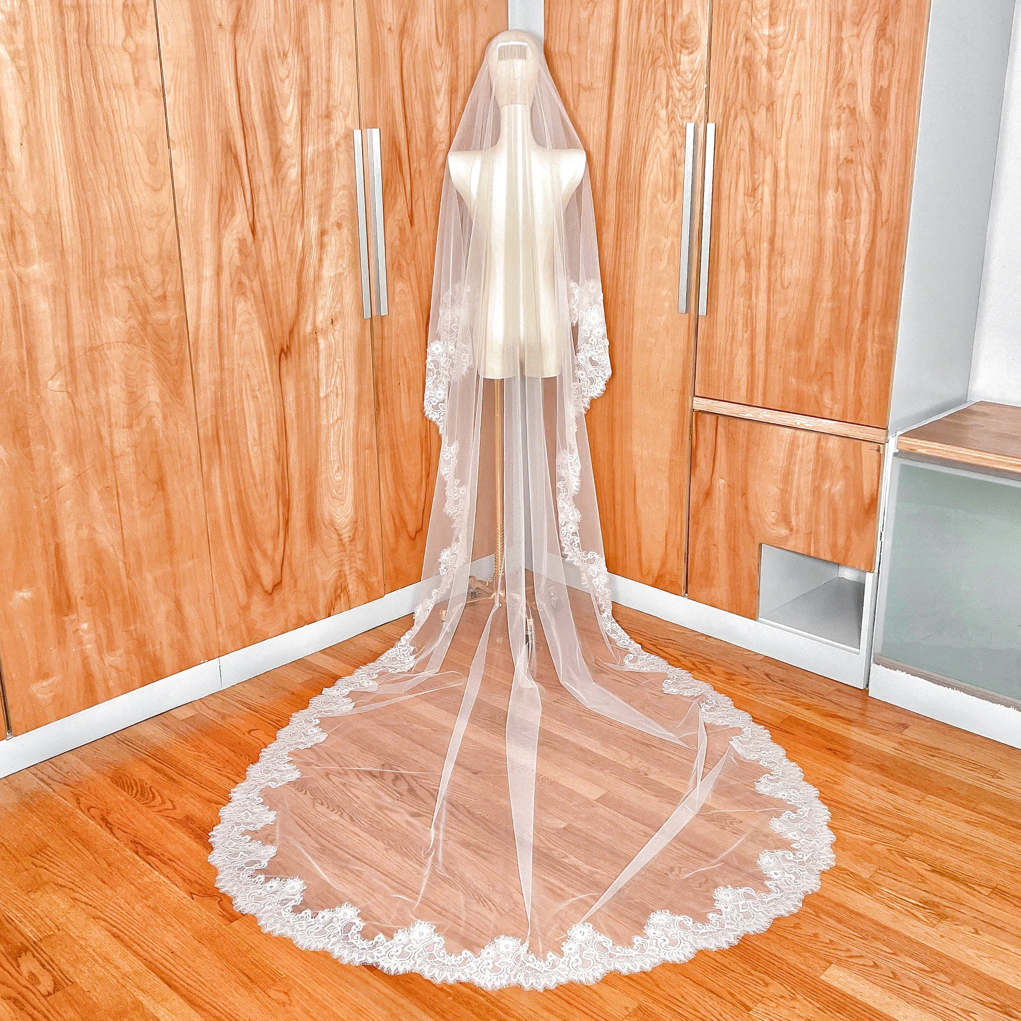 Detail view of how the Chantilly lace drop wedding veil with blusher attaches to the head of a mannequin.