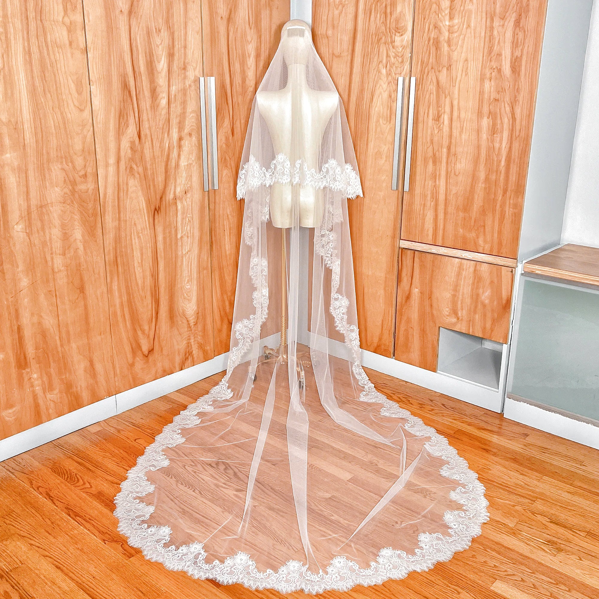 Cathedral length Chantilly lace drop wedding veil with blusher shown from the back on a mannequin.