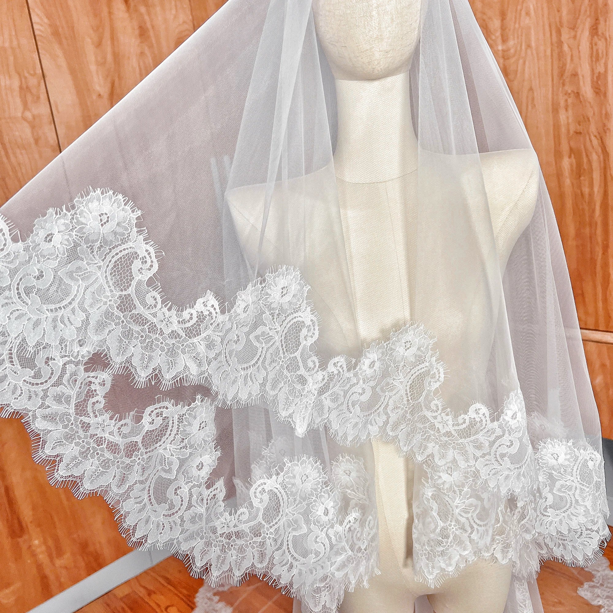 Close-up of the delicate floral Chantilly lace trim on a cathedral length drop wedding veil.