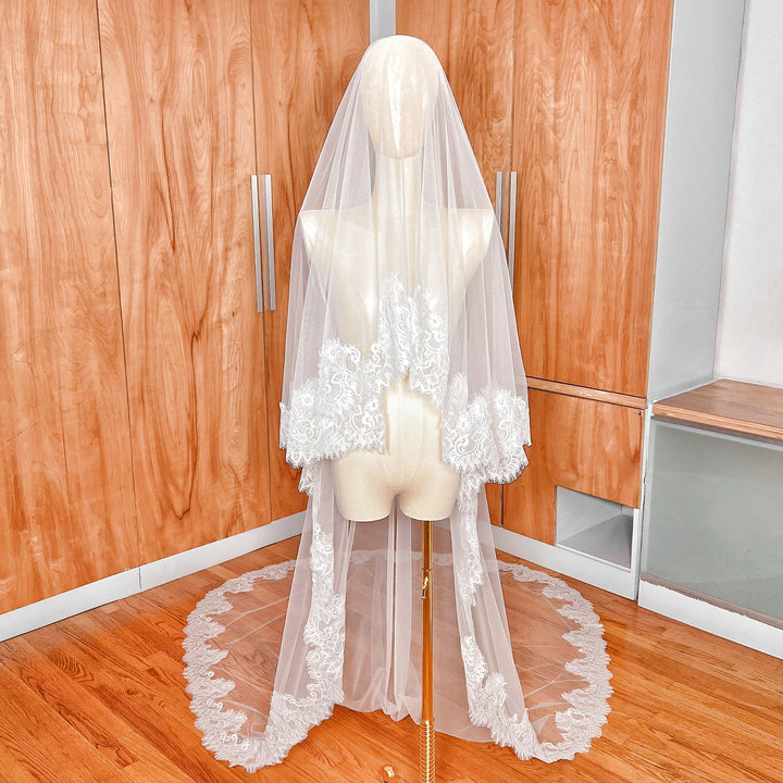 Front view of a Chantilly lace drop wedding veil with blusher covering the face of a mannequin.