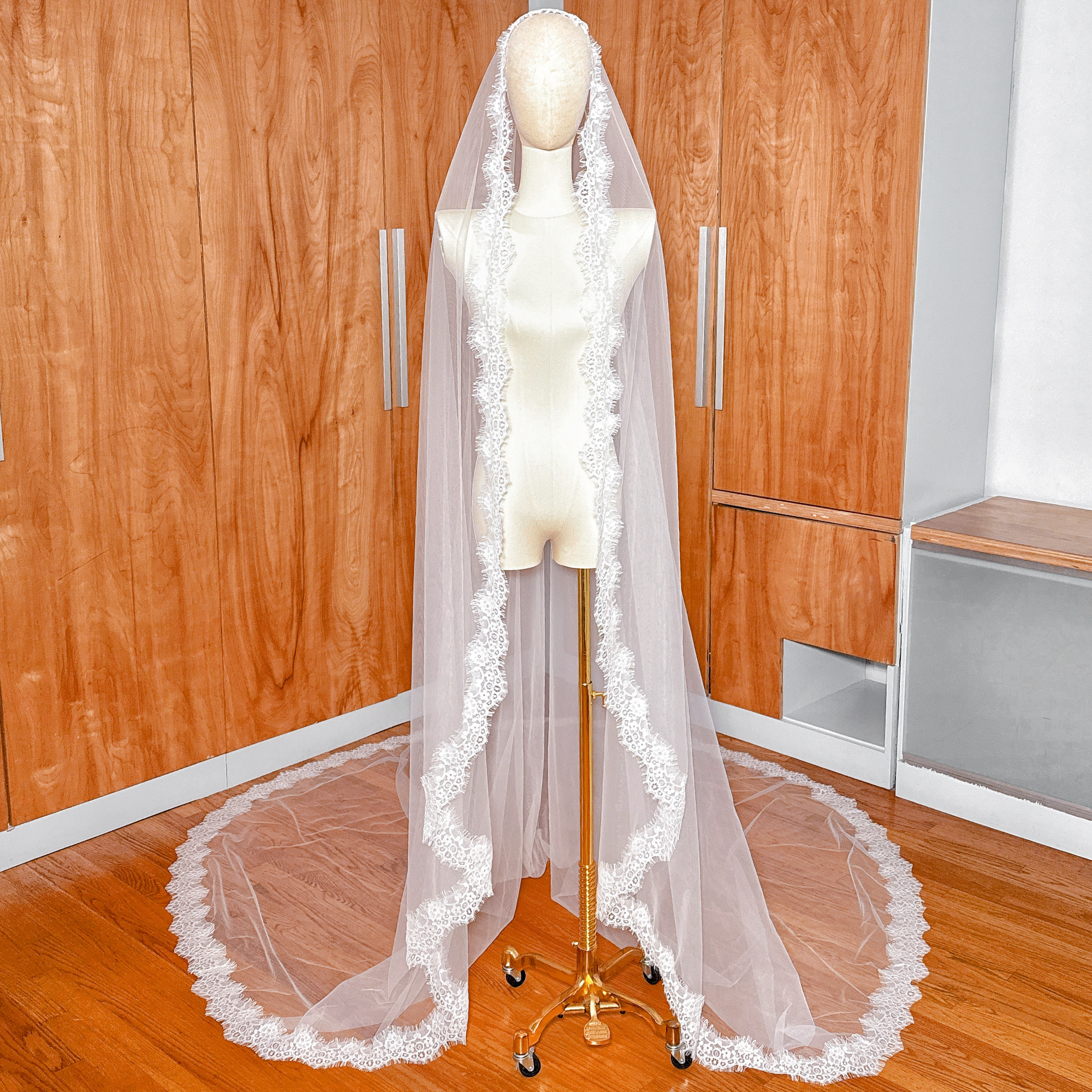 Front view of a cathedral length Chantilly lace mantilla veil draped over a bridal mannequin.