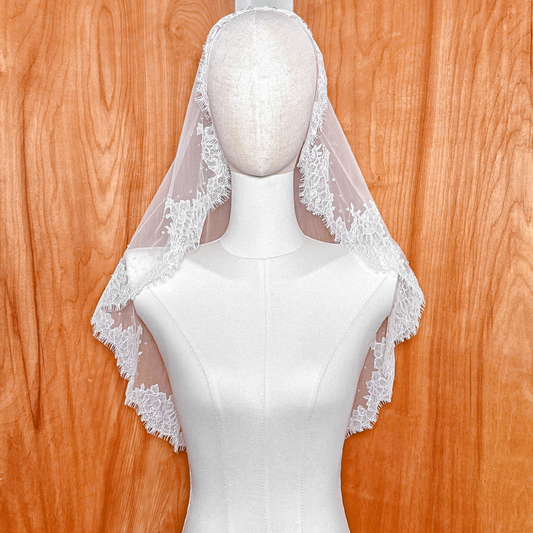 Front view of an elbow-length Chantilly lace mantilla veil displayed on a mannequin.
