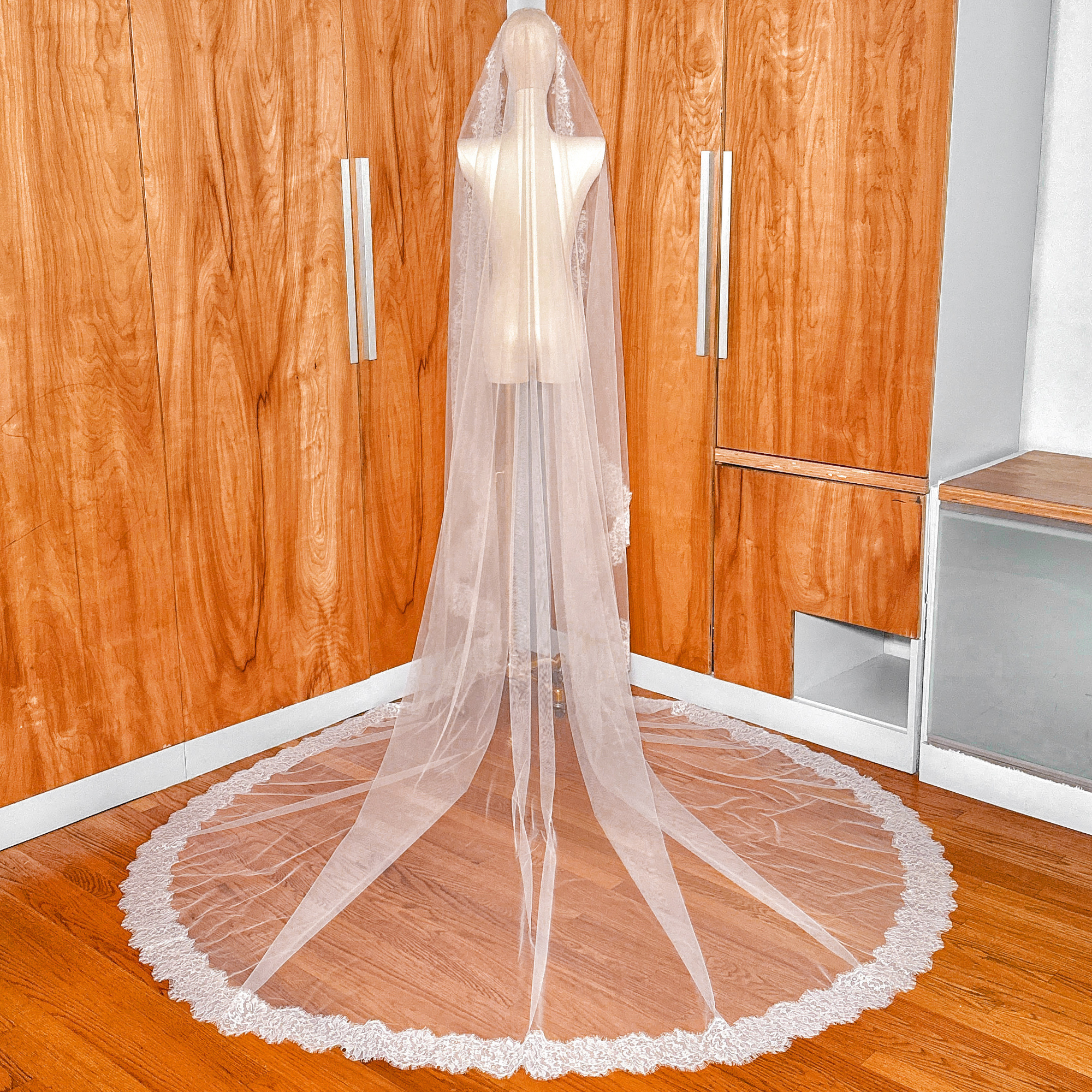 Back view of a Chantilly lace mantilla veil draped over a mannequin to show the cathedral length flow.