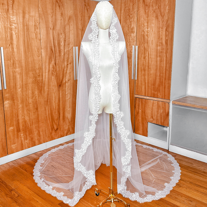 A cathedral length Chantilly lace mantilla wedding veil draped over a bridal mannequin to show the full 108-inch span.