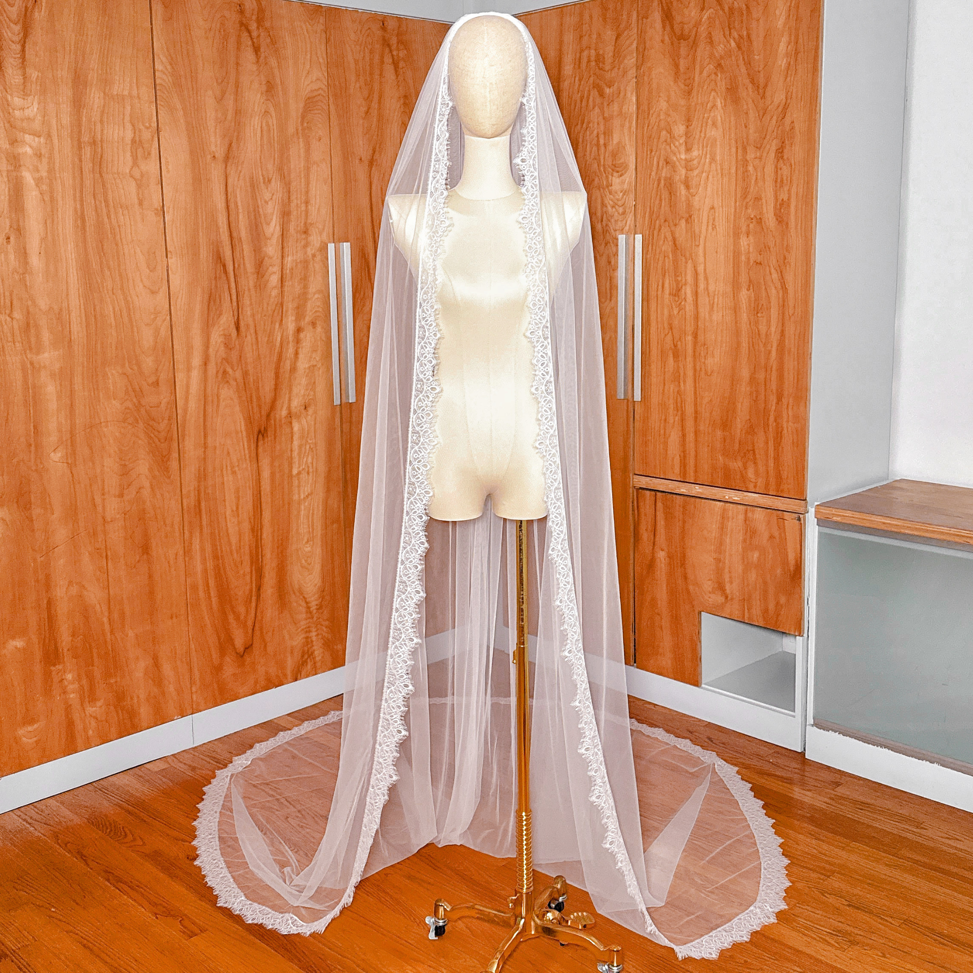 A cathedral length Chantilly lace veil draped elegantly on a mannequin.