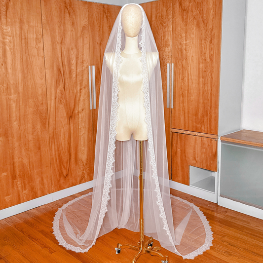A cathedral length Chantilly lace veil draped elegantly on a mannequin.