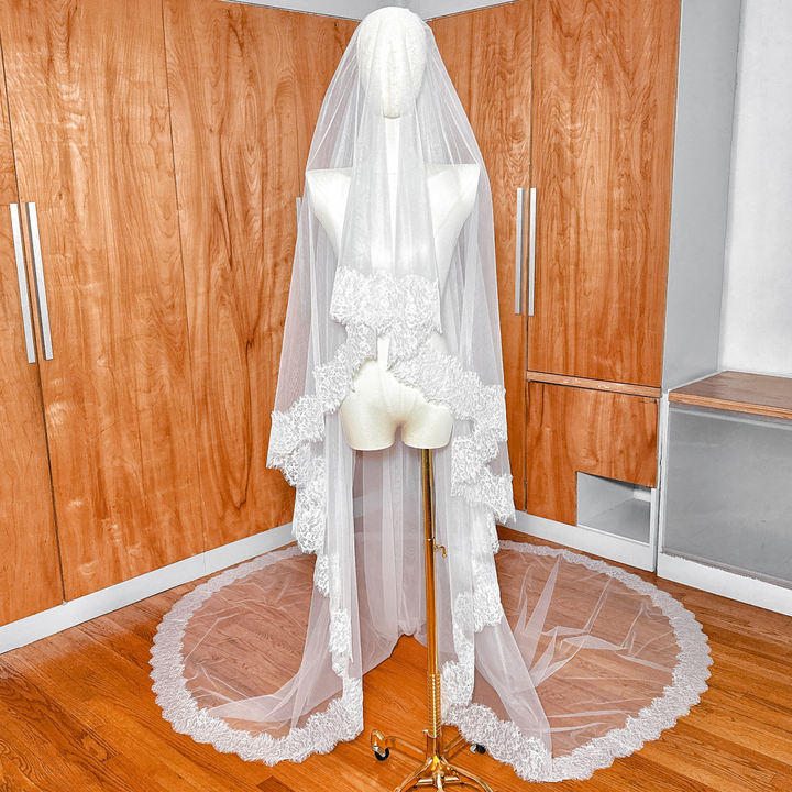 Cathedral length Chantilly lace wedding veil with blusher displayed on a bridal mannequin.
