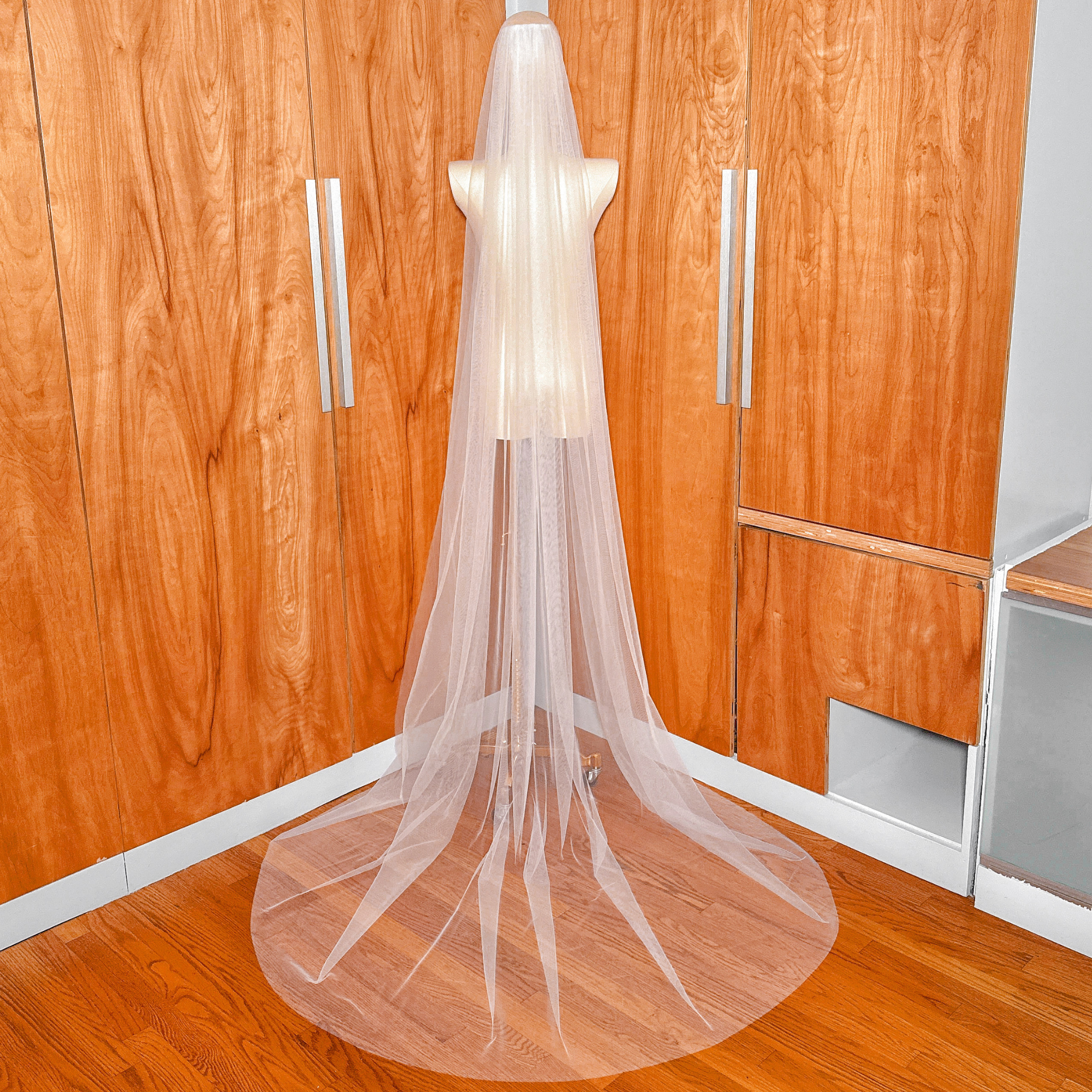 Full back view of a simple chapel length raw edge veil showing its floor-length drape and sheer tulle quality.