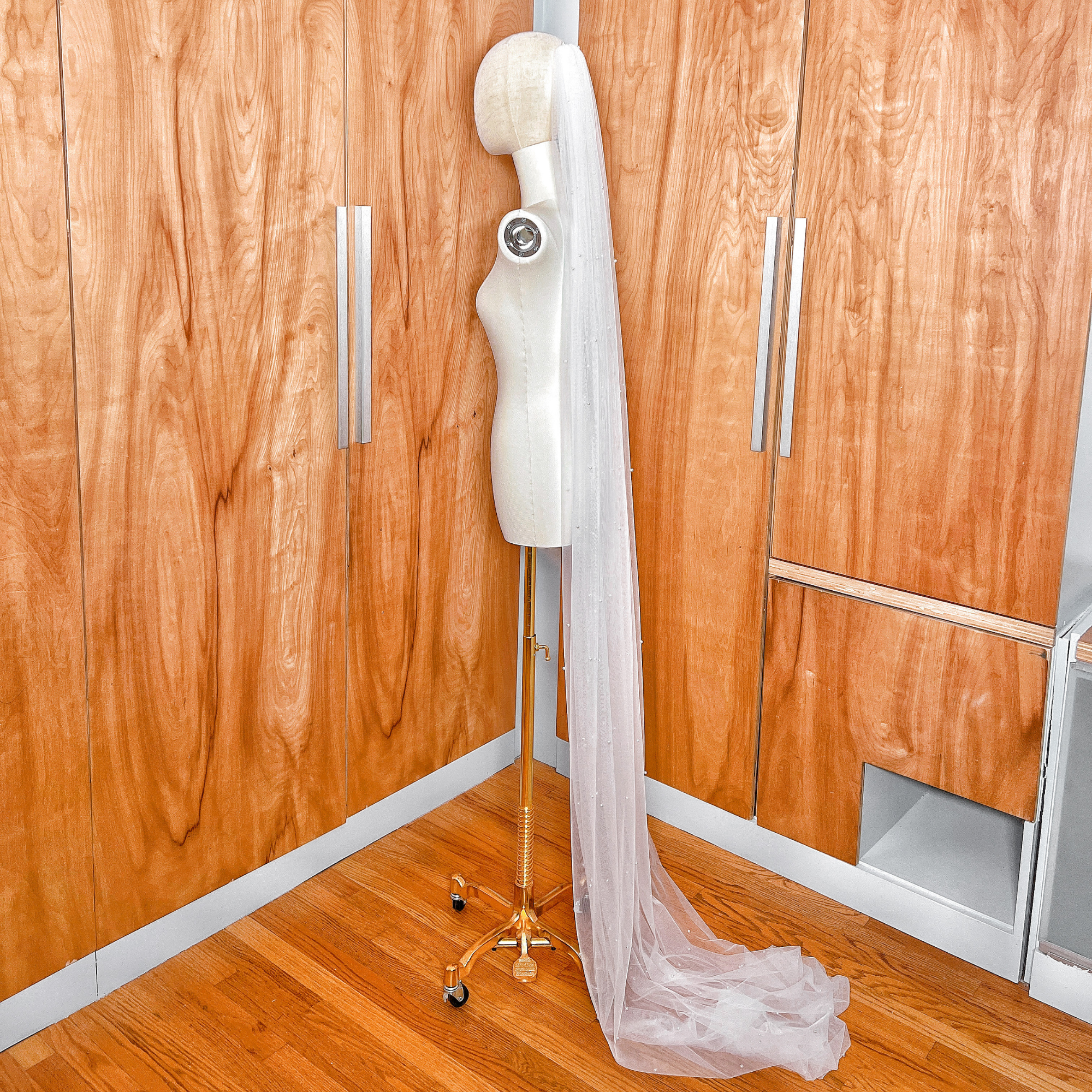 The secure metal comb attachment of a scattered pearl wedding veil, showing how it sits atop the soft tulle layers.