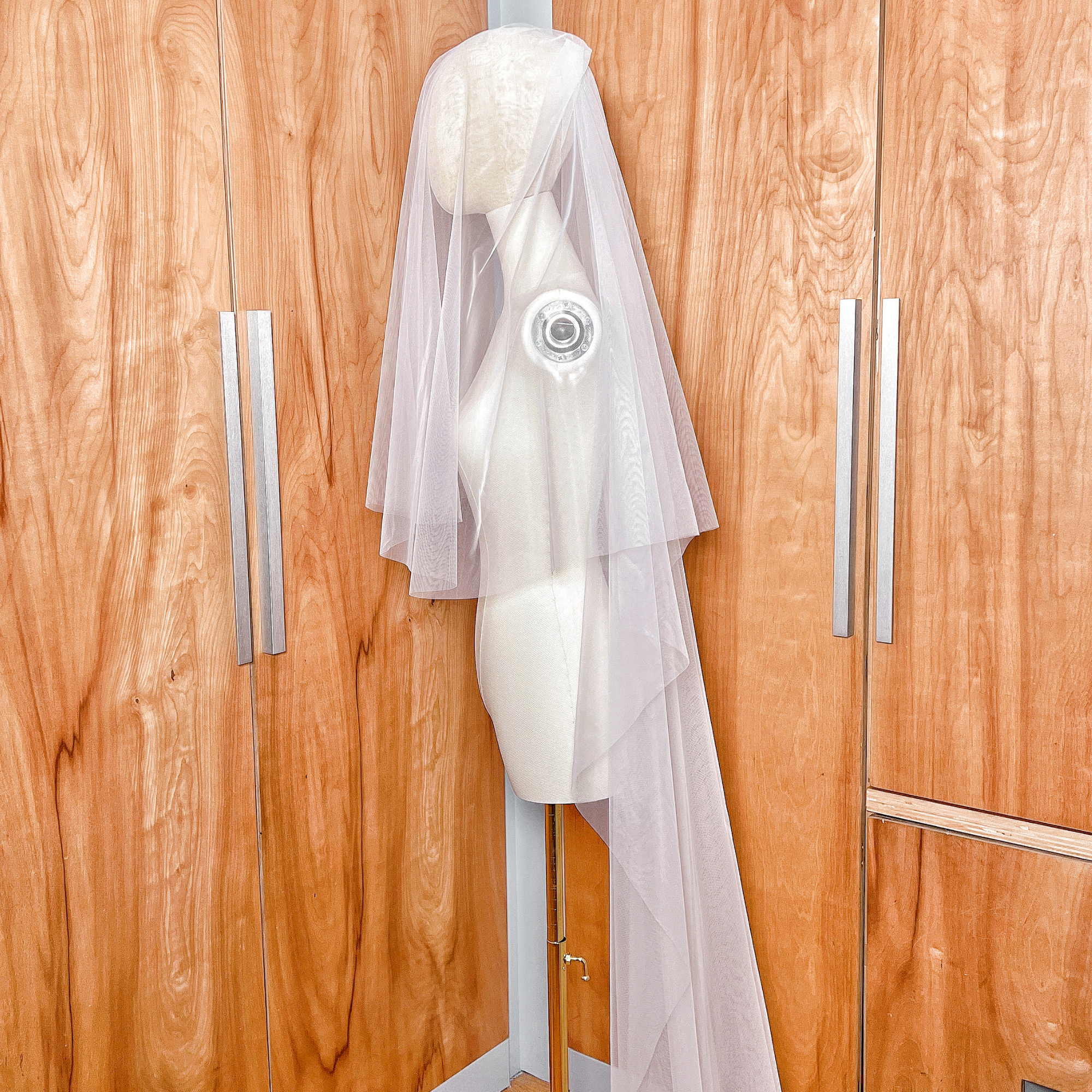 Side profile of a chapel length wedding veil with a blusher tier, highlighting the lightweight tulle and simple raw edge design.