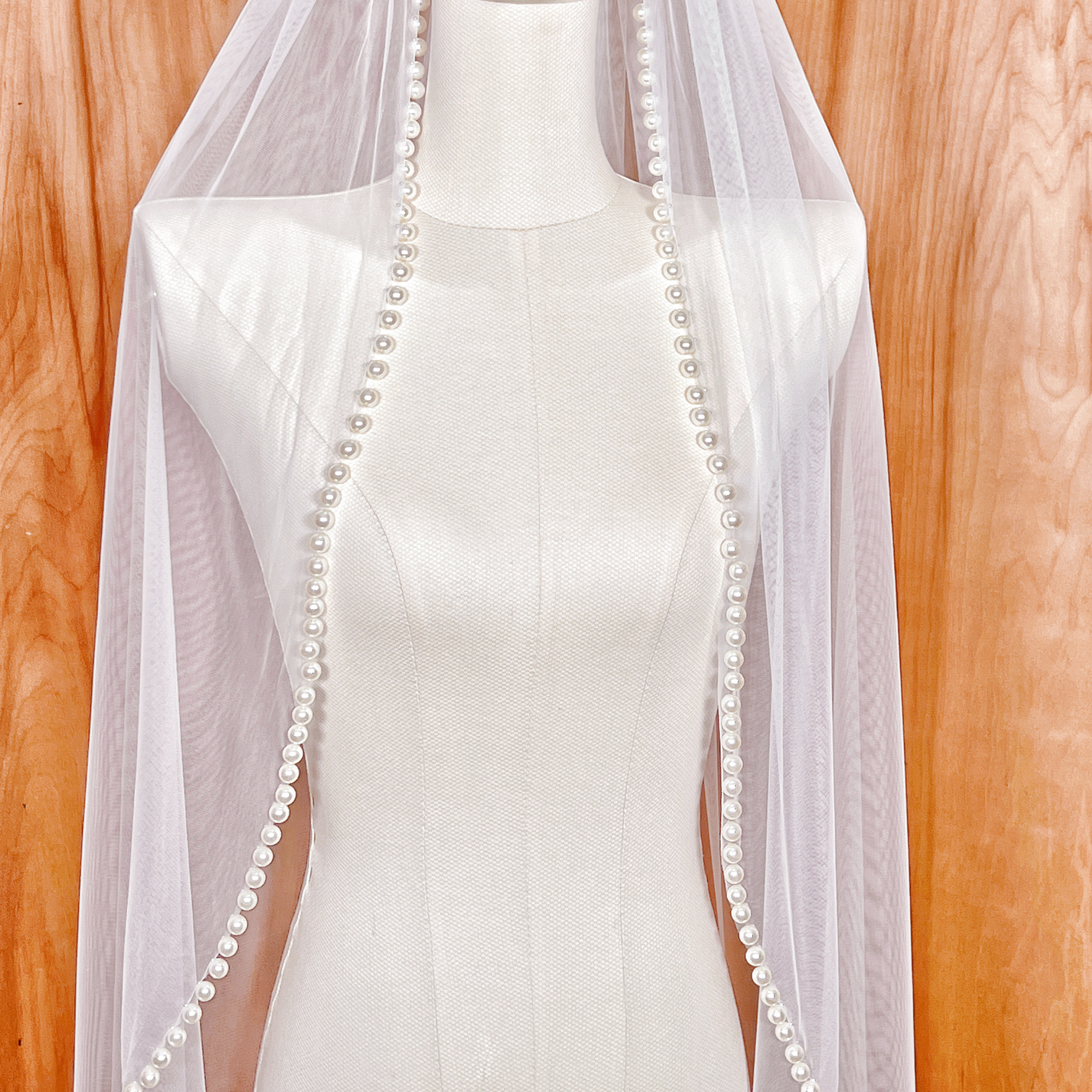 A classic hip-length wedding veil with a structured pearl trim, perfect for minimalist bridal gowns.