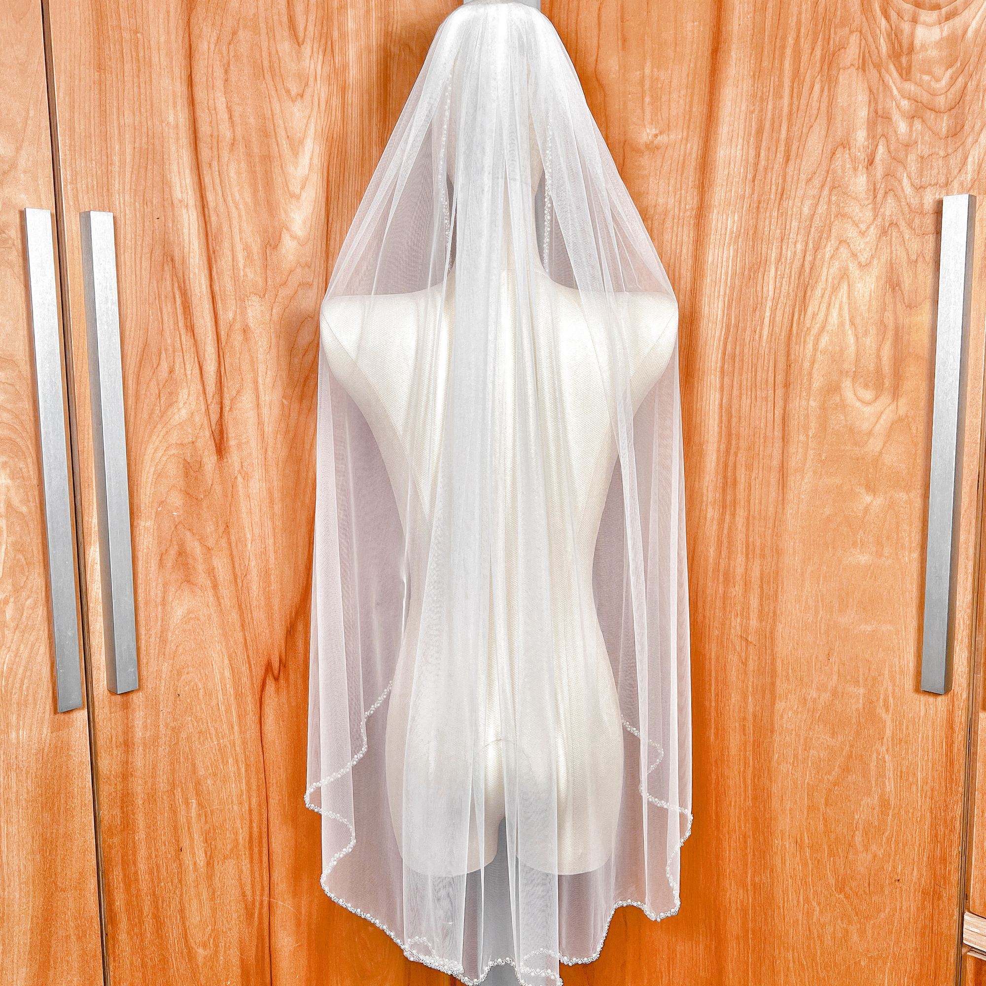 Rear view of a classic soft tulle beaded edge wedding veil in fingertip length.