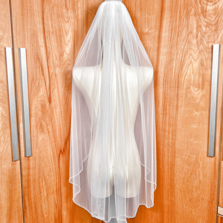 Rear view of a classic soft tulle beaded edge wedding veil in fingertip length.