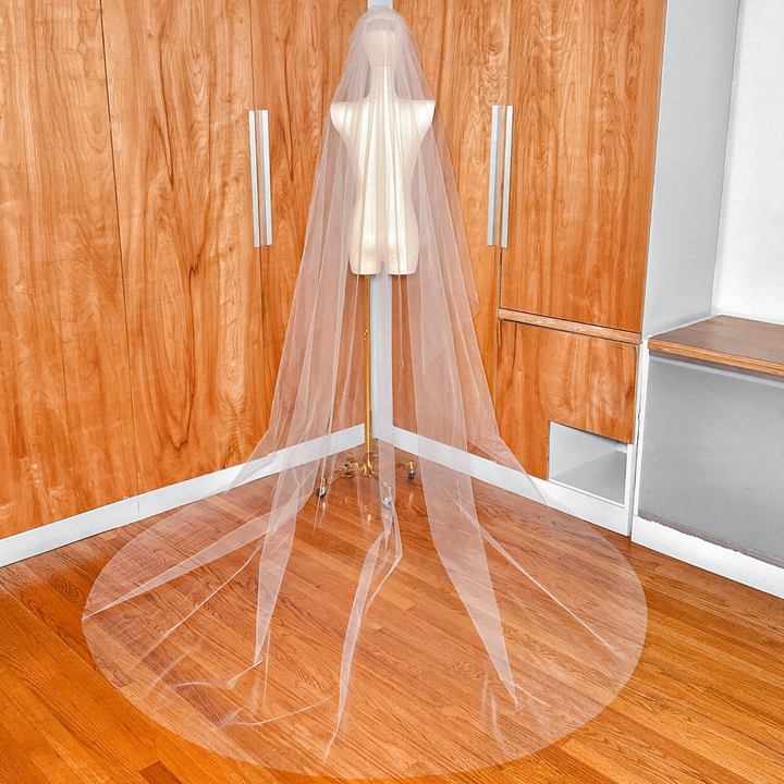 Classic two-tier cathedral tulle wedding veil showing the blusher pulled forward over the face.