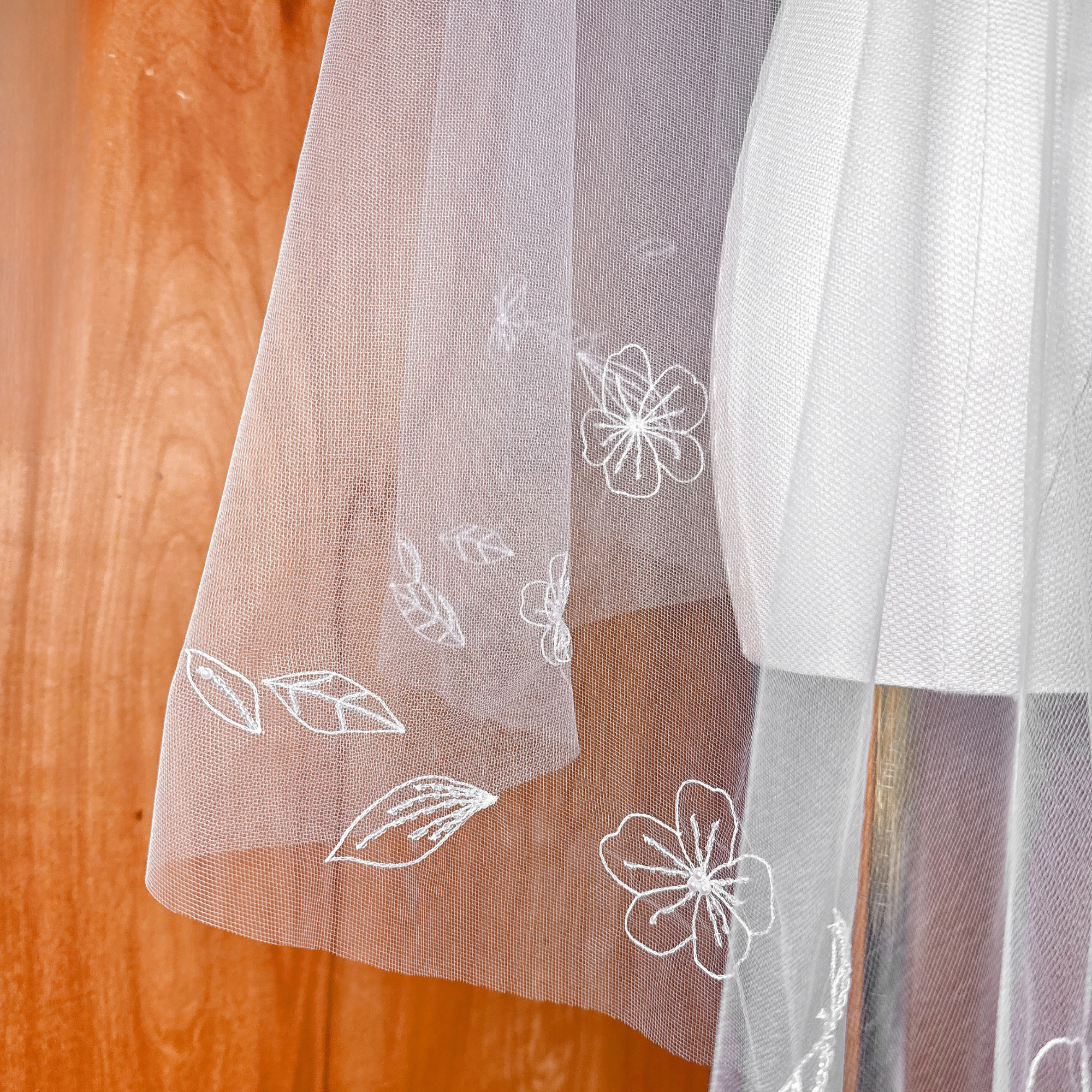 Detailed close-up of intricate 3D hand-embroidered flower petals on a soft bridal tulle veil.