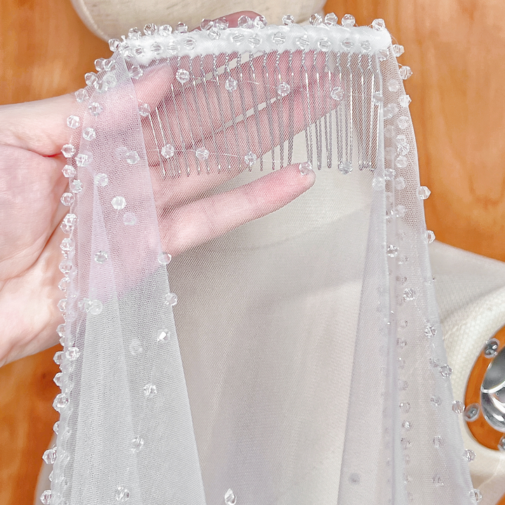Close-up detail of the hand-beaded crystal scalloped edge on the fingertip-length Crystal Edge Mantilla Wedding Veil.