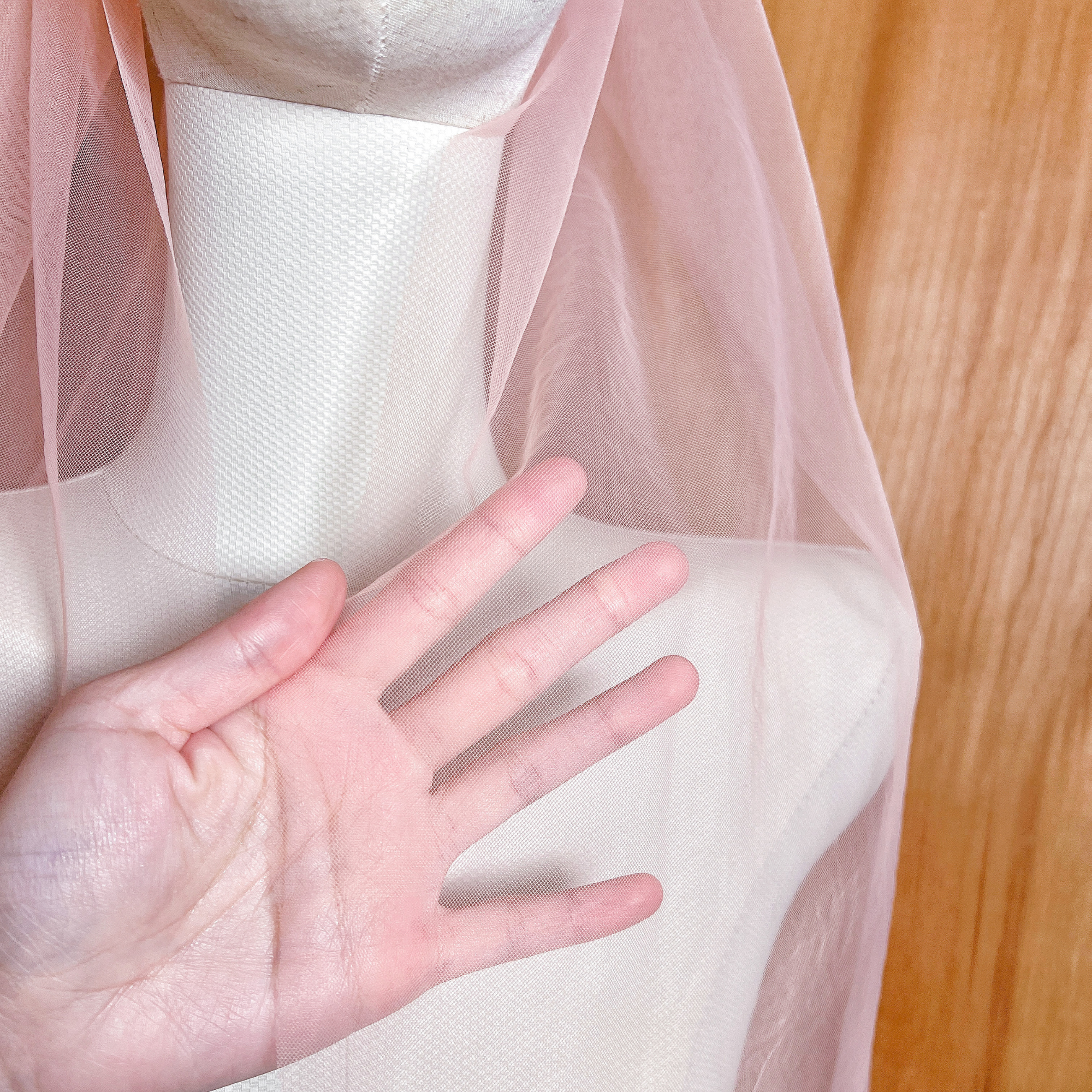 Close-up of the delicate coral wedding veil fabric showing the soft tulle texture and clean raw edge.
