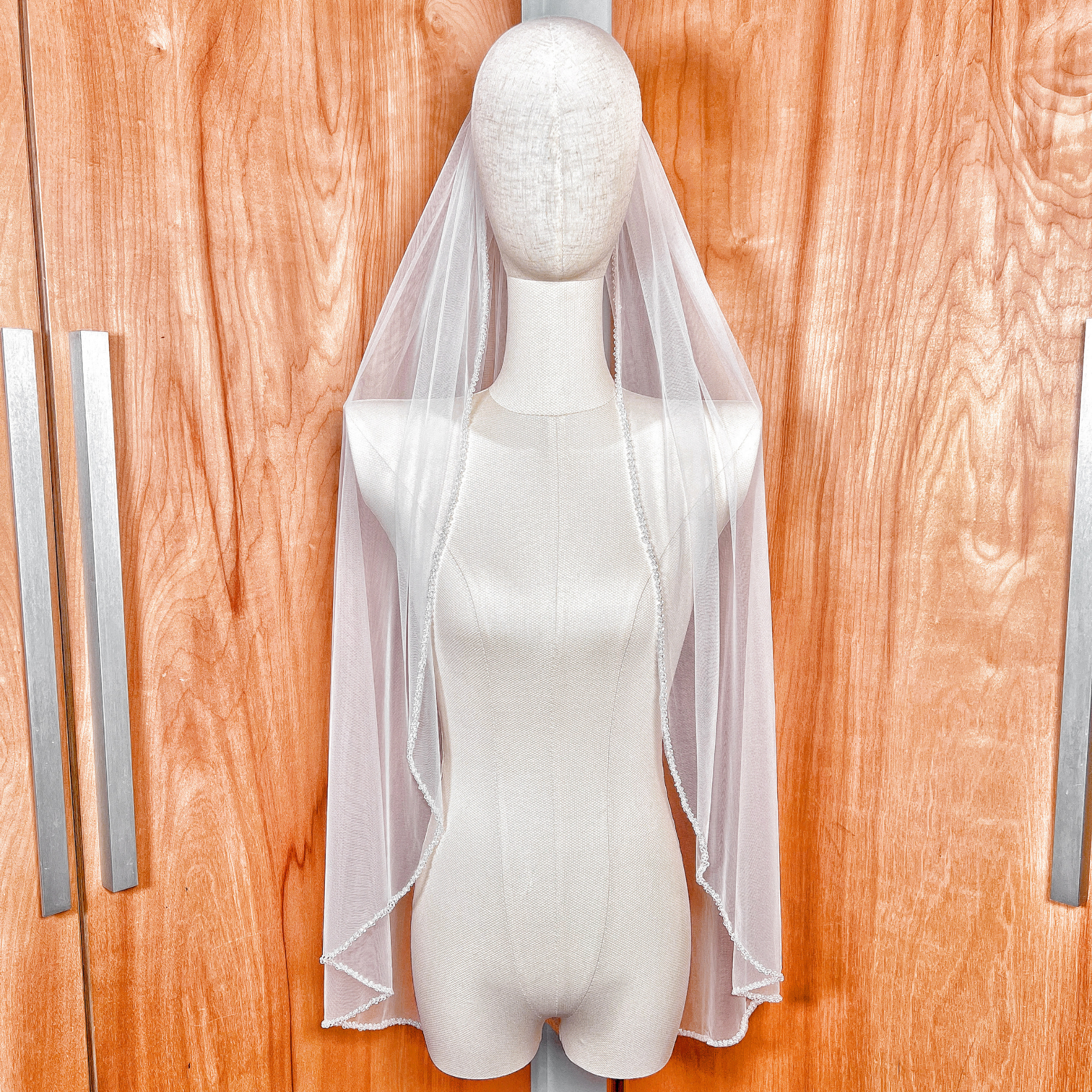Fingertip length crystal beaded wedding veil displayed on a bridal mannequin.