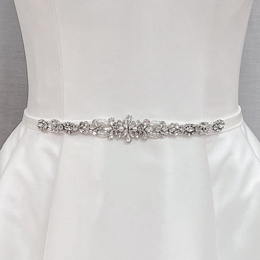 Crystal rhinestone and pearl bridal belt displayed on a dress mannequin.