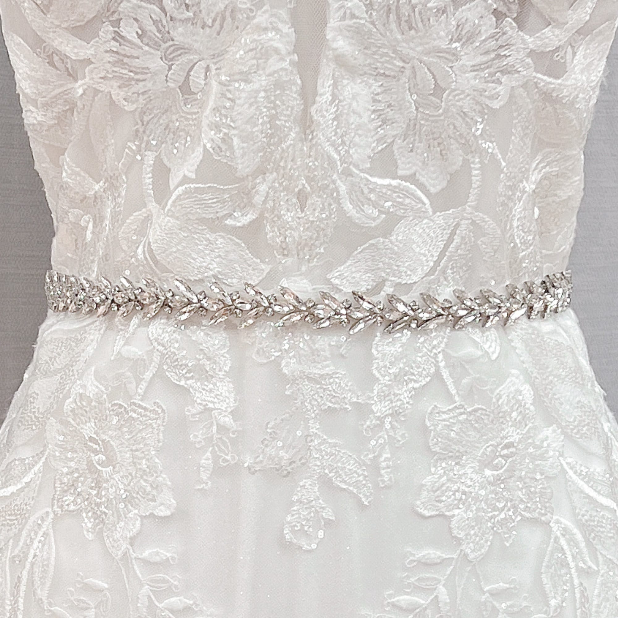 Close-up view of a silver beaded bridal belt and crystal rhinestone wedding dress sash displayed on a bridal mannequin.