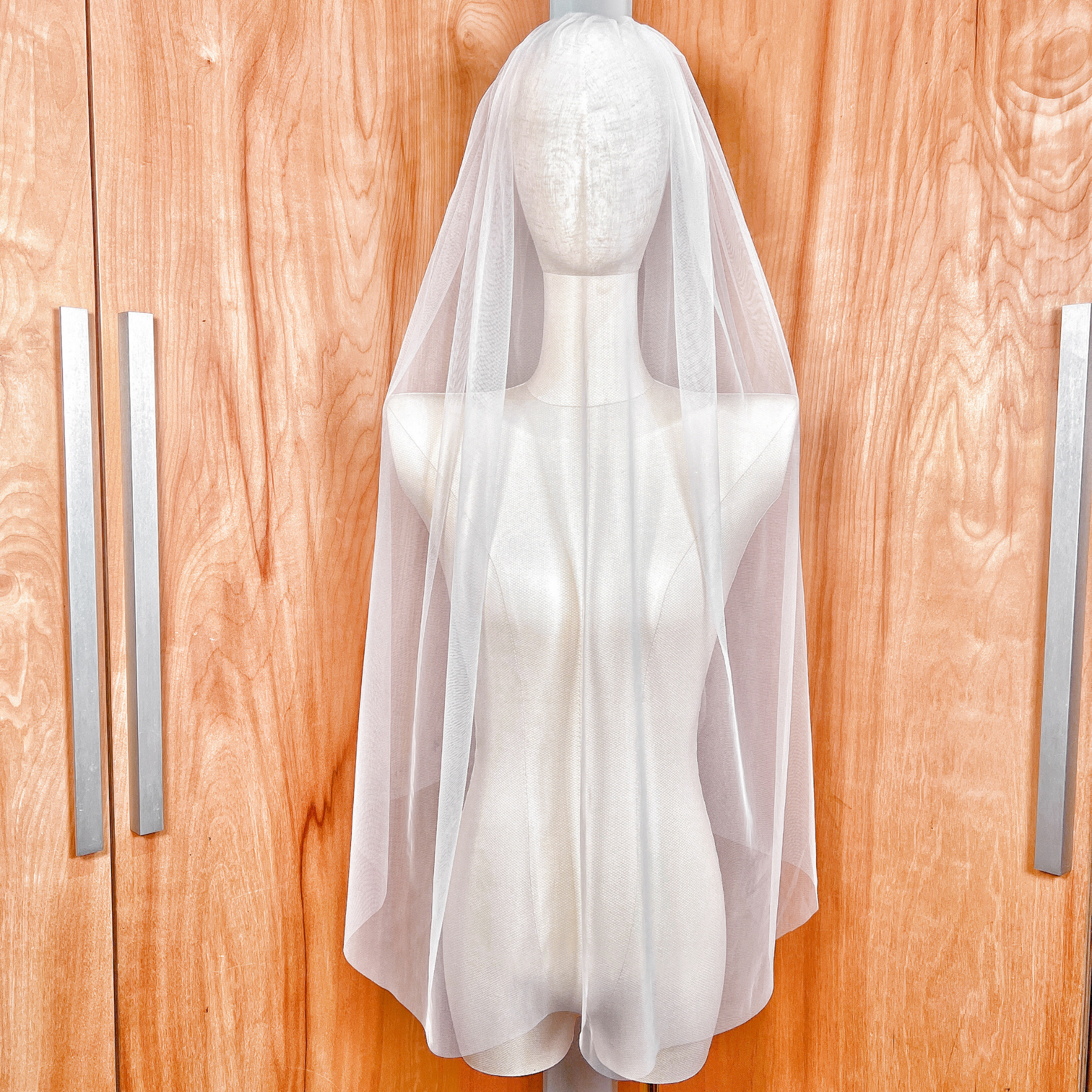 Front view of a sheer white detachable blusher veil with a minimalist raw edge finish.