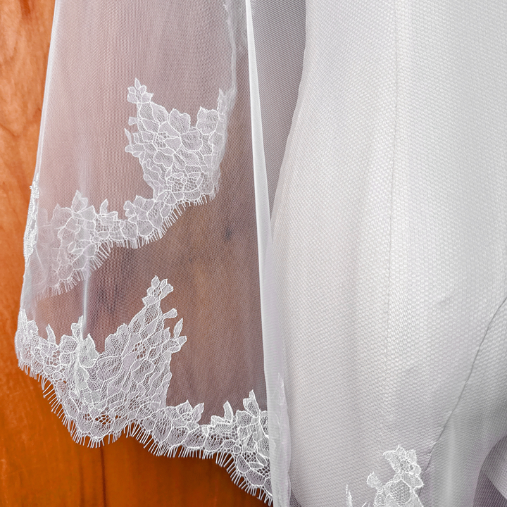 Close-up of the intricate floral eyelash lace detail on a fingertip length Chantilly mantilla bridal veil.