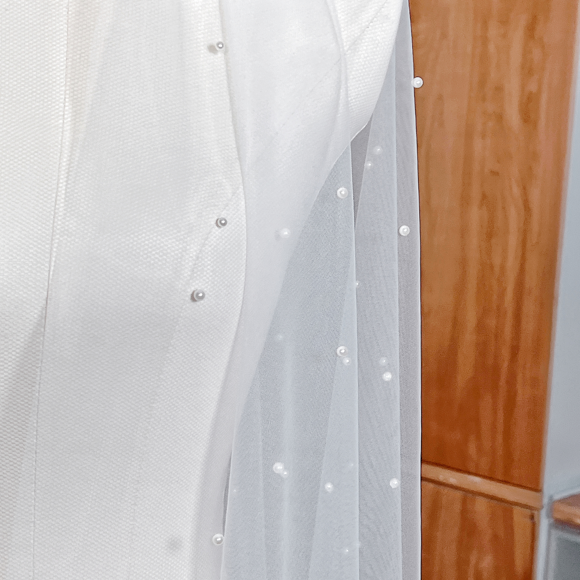 Close-up of delicate scattered pearls on a cascading wedding veil showing the intricate pearl placement and sheer fabric detail.