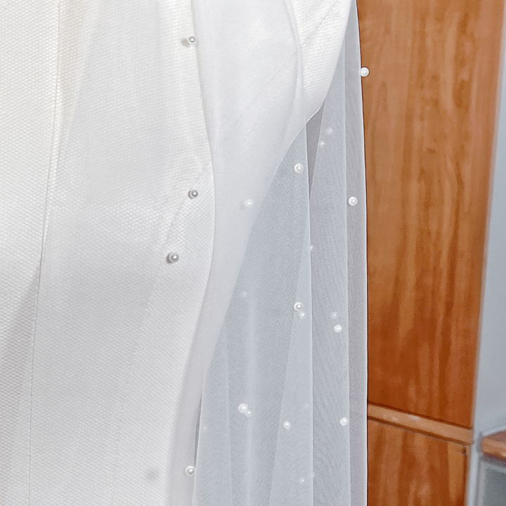 Close-up of delicate scattered pearls on a cascading wedding veil showing the intricate pearl placement and sheer fabric detail.