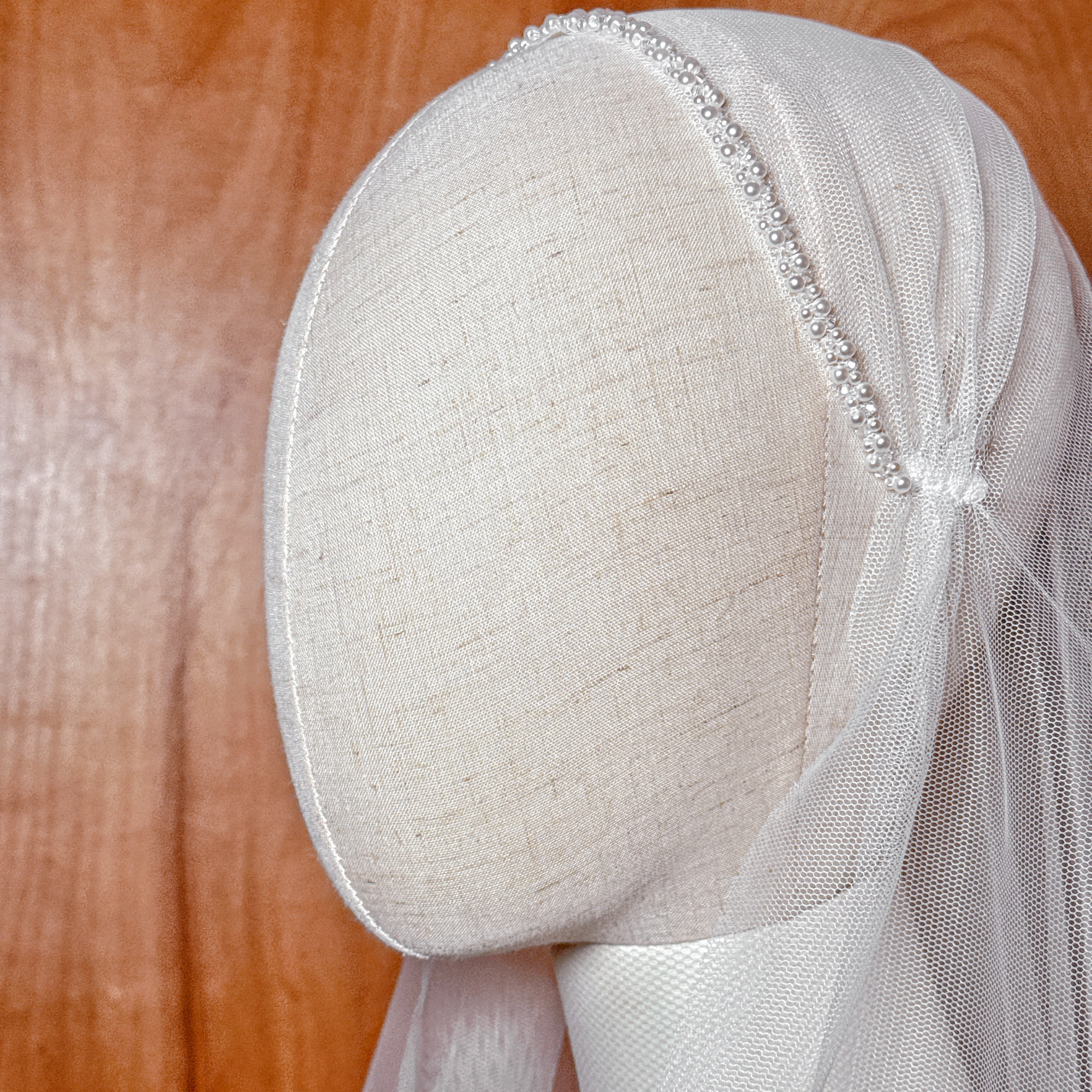 Close-up detail of the hand-beaded pearl embellishments on a Juliet cap veil in fingertip length.