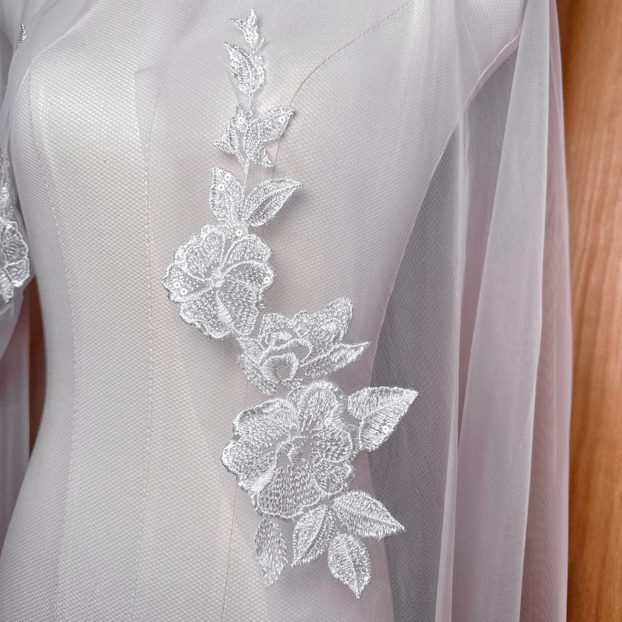 Close-up detail of intricate floral lace appliques on a sheer ivory waltz length bridal veil.