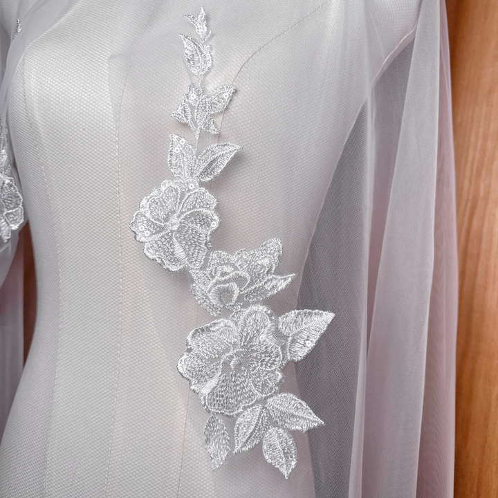 Close-up detail of intricate floral lace appliques on a sheer ivory waltz length bridal veil.