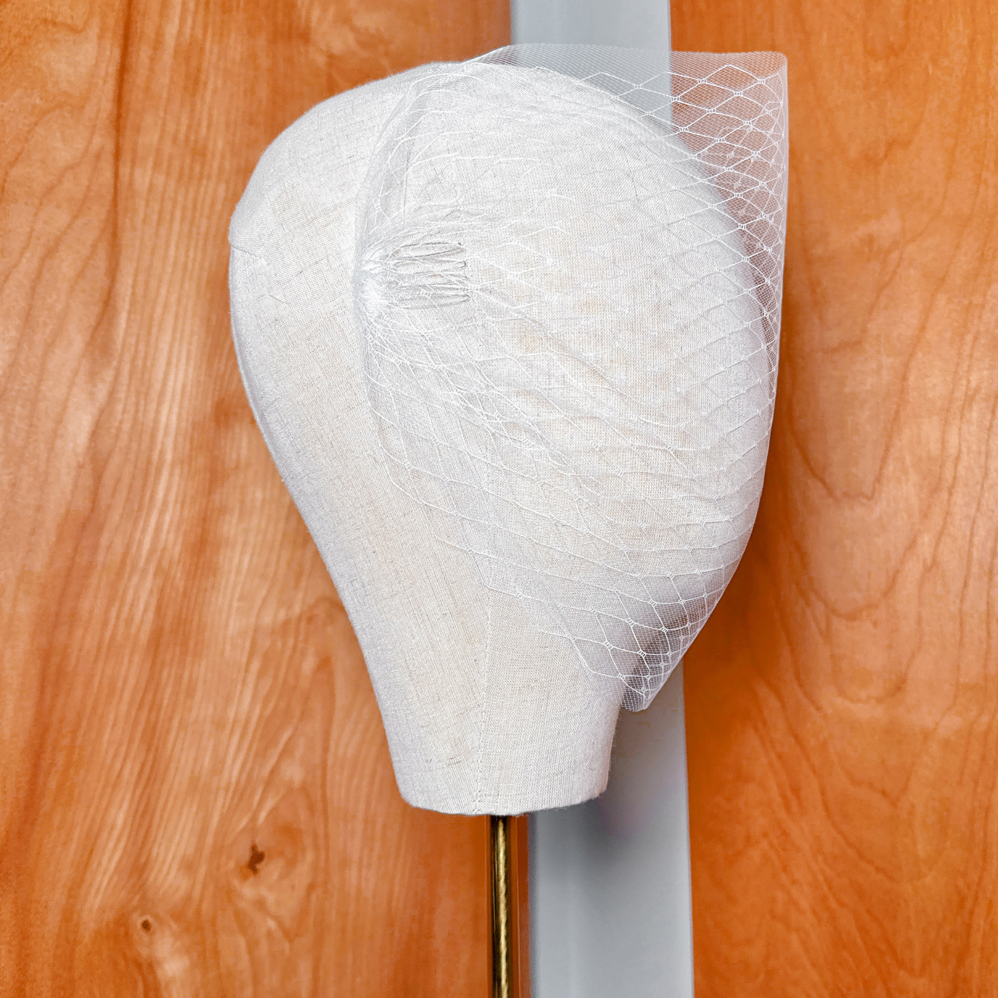 Close-up view of the fine gather and soft texture of a double layer bandeau wedding veil on a display form.