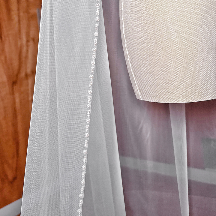 Classic ivory cathedral length wedding veil with a shimmering pearl trim, perfect for formal church ceremonies.