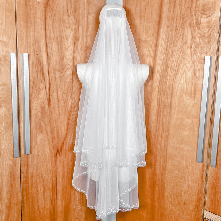 Back view of an elegant two-tier wedding veil with beaded edges draped in fingertip length.