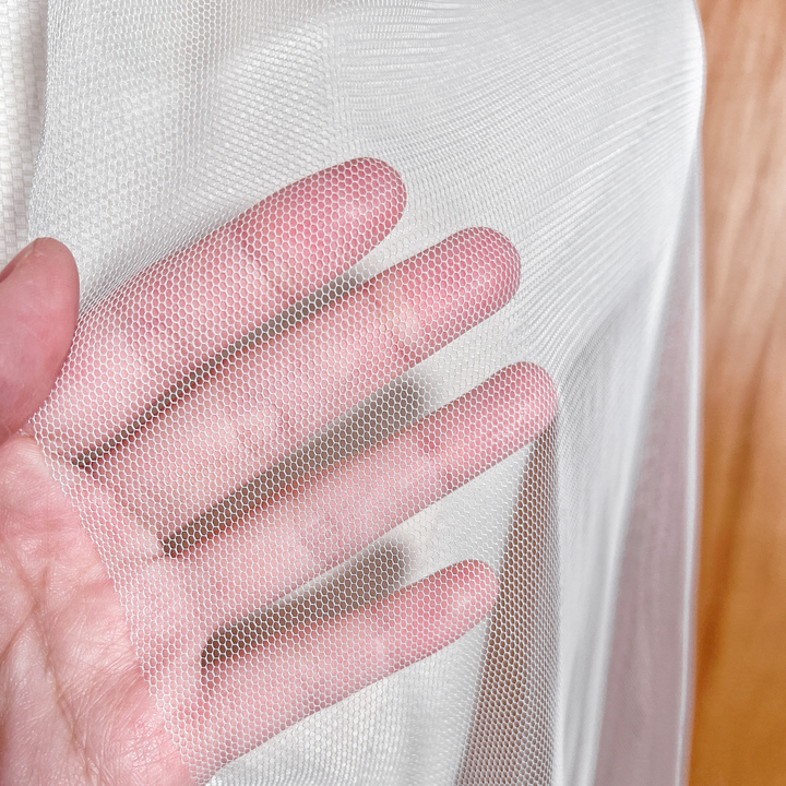 Close-up detail of the sheer English net fabric and raw edge on a waltz length wedding veil.