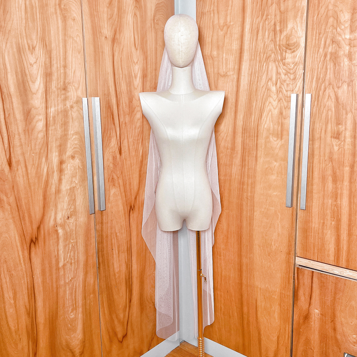 Full-length view of an English net waltz length wedding veil showing the soft, airy drape and raw cut edge.