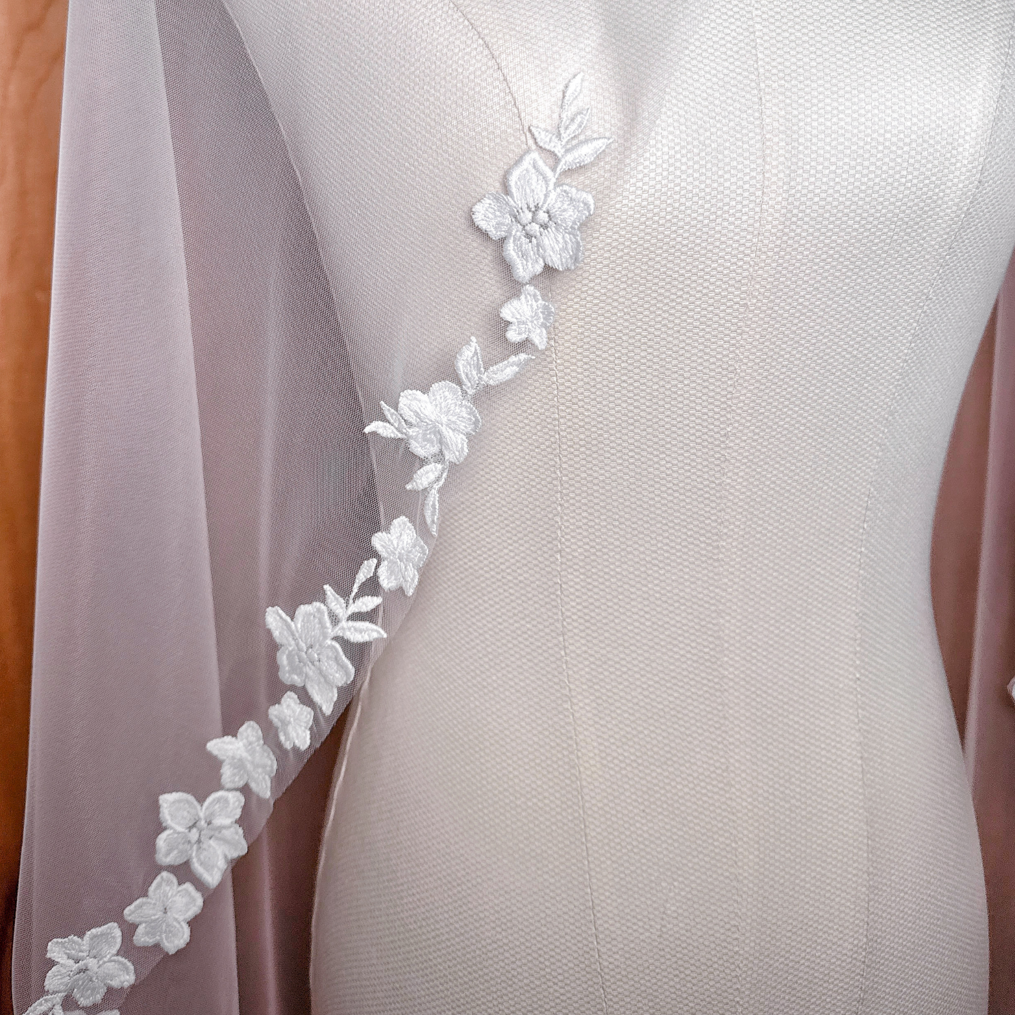 Close-up detail of cascading floral lace embroidery on a fingertip length bridal veil.