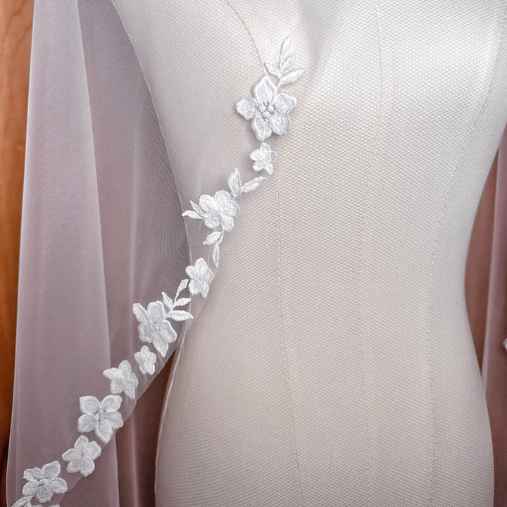 Close-up detail of cascading floral lace embroidery on a fingertip length bridal veil.