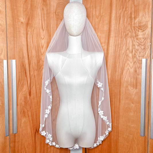 Front view of a fingertip length bridal veil with cascading floral lace displayed on a mannequin.