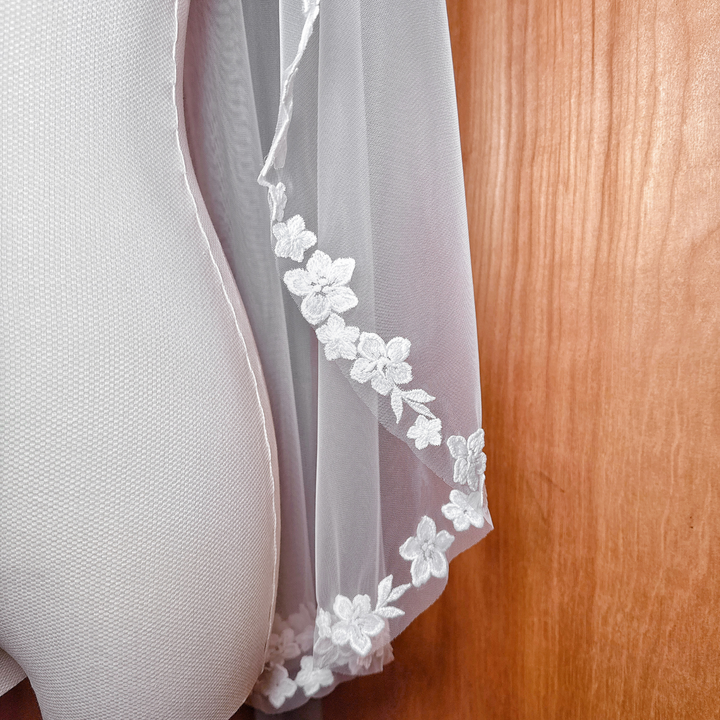 High-resolution texture shot of the cascading floral lace on a fingertip length bridal veil.